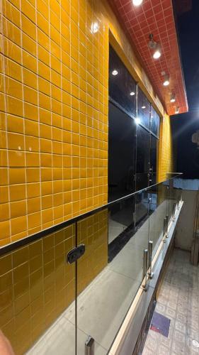 a bathroom with yellow tiled walls and mirrors at Pousada Rafael in Juazeiro do Norte