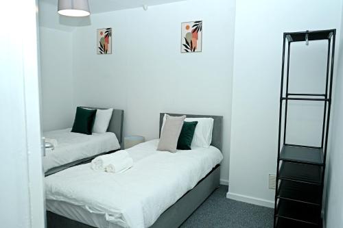 two beds in a room with white walls at Contractor & Family Haven, Sleeps 7, Parking & Garden in Wednesfield