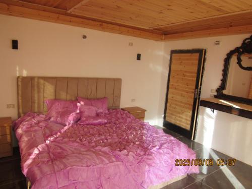 a bedroom with a large bed with pink sheets at اكواخ الملول عجلون 2 in Ajloun