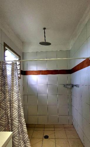 a bathroom with a shower with white tiles and a window at MJA's Retreat in Arorangi