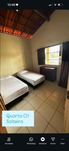 two beds in a room with a window at Casas de Praia do Coqueiro com AR e varandas in Luis Correia