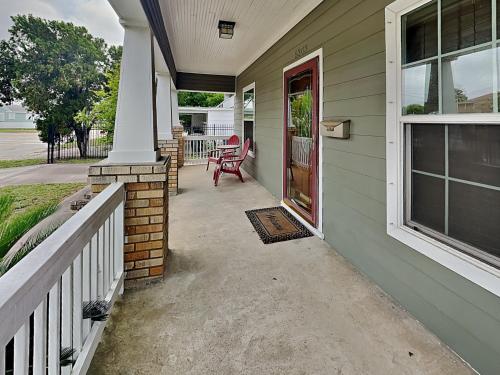 a front porch of a house with a red door at Hidden Haven in Galveston