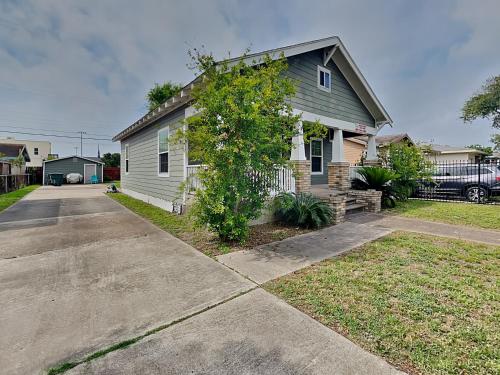 a white house with a tree in front of a driveway at Hidden Haven in Galveston