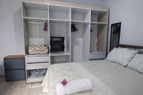 a bedroom with a large bed and white shelves at Quarto Divas na Sakura House in Indaiatuba