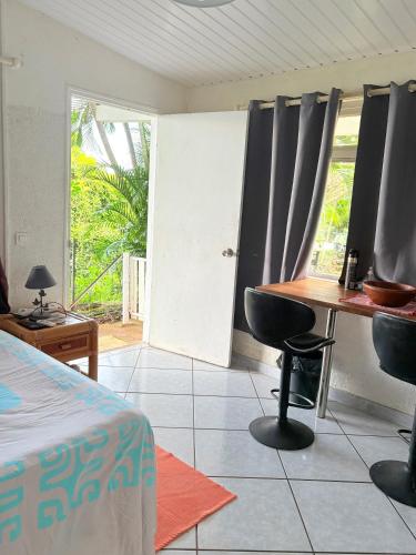 a room with a bed and a table and a window at Bungalow Pamatai Sky in Faaa