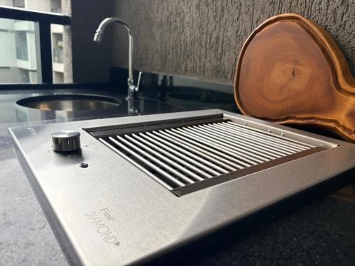 a kitchen counter with a metal grate and a sink at Beira mar Flat Deluxe Nomar Carneiros Ecoliving Réveillon in Tamandaré