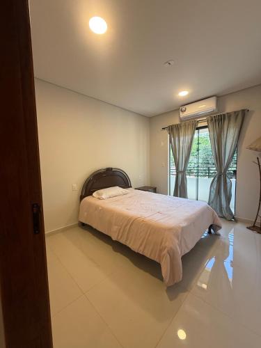 a bedroom with a bed and a large window at Residencia Pura Vida in Capiatá