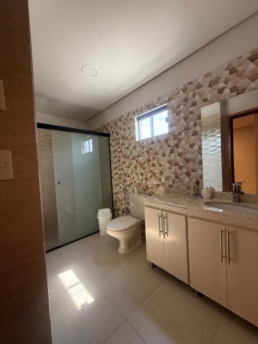 a bathroom with a toilet and a sink and a mirror at Residencia Pura Vida in Capiatá