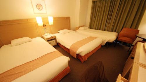 a hotel room with two beds and a chair at Chateraise Gateaux Kingdom Sapporo in Sapporo