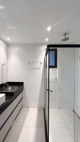 a white bathroom with a sink and a shower at Lindo Studio Com Vista para Cidade in Campo Grande