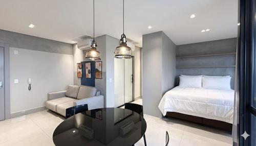 a bedroom with a bed and a couch and a table at Lindo Studio Com Vista para Cidade in Campo Grande