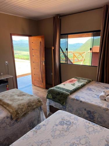 a bedroom with two beds and a large window at Pousada Mirante Das Serras Ibicoara-BA in Ibicoara