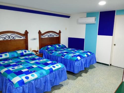 two beds in a room with blue and white at Hotel Los Cedros in Martínez de La Torre