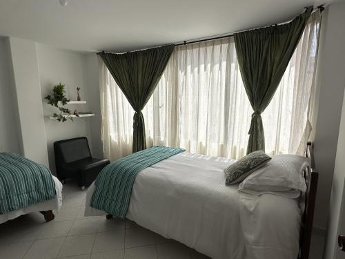 a bedroom with a bed and a chair and a window at Siga Sumercé Apartamento completo centro de Duitama in Duitama