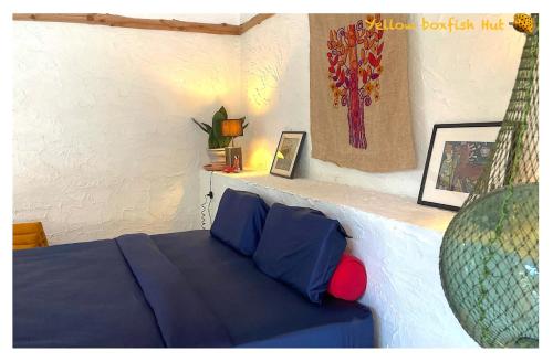 a bedroom with a bed with blue sheets and a vase at Yellow Boxfish Hut in Ban Thong Phlu