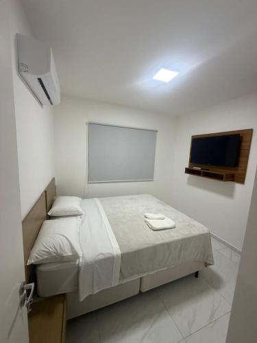 a bedroom with a bed and a flat screen tv at Apartamento Loretto in Espirito Santo Do Pinhal