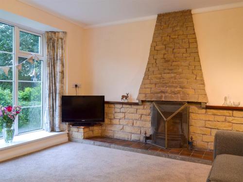 a living room with a stone fireplace and a flat screen tv at The Mill Cottage in Ault Hucknall