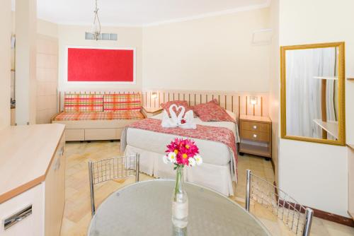 フロリアノポリスにあるPousada Lozaltiのベッドルーム1室(ベッド1台、花瓶付きのテーブル付)