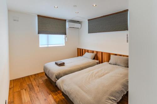 two beds in a room with two windows at Myoko Cedric Villa 01 in Myoko
