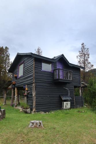 a black house with a balcony on top of it at Cabaña Casa Morada in Futaleufú