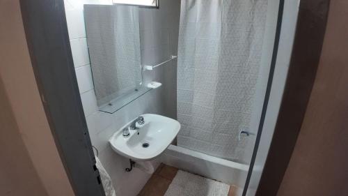 a white bathroom with a sink and a mirror at Departamento Escobar in Belén de Escobar