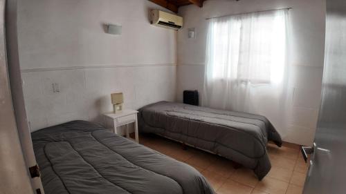 two beds in a small room with a window at Departamento Escobar in Belén de Escobar
