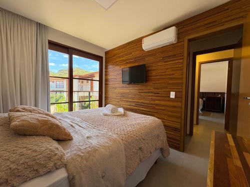 a bedroom with a bed and a tv on a wall at Diamantino Residence - apt 07 CalmariaMucuge in Mucugê