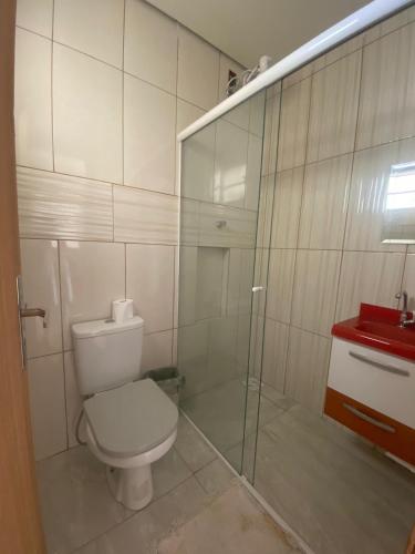 a bathroom with a toilet and a glass shower at Suíte por do sol 2 casa compartilhada in Xangri-lá