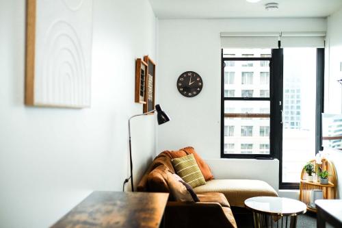 a living room with a couch and a clock on the wall at Top Floor - Secure Parking - Great Location - Quiet - City Ciew in Wellington