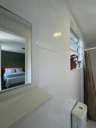 a white bathroom with a mirror and a bed at Sítio Mais Lindo do Mundo in Ilha de Guaratiba