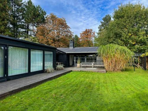 a black house with a lawn in front of it at Stylish House Between Beach And Forest In Tisvilde in Tisvilde
