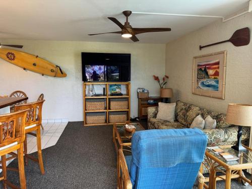a living room with a couch and a surfboard on the wall at Alii Villas in Kailua-Kona