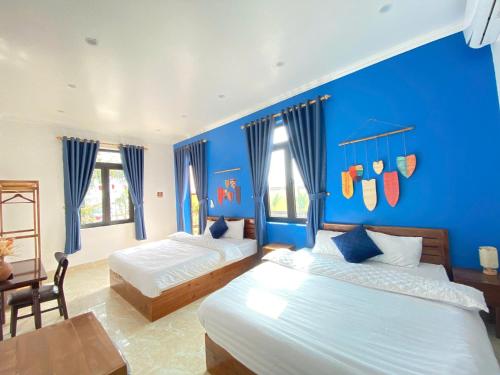 a bedroom with two beds and a blue wall at Peace Homestay Hoa Lư in Xuân Sơn