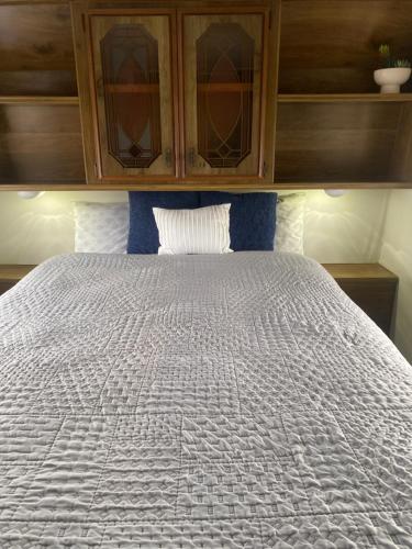 a bedroom with a white bed with a wooden cabinet at Cozy Private 5th Wheel AC Pet Friendly in Tucson