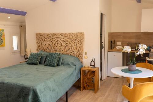 a bedroom with a green bed and a table at Studio le nid avec piscine partagée in Flayosc