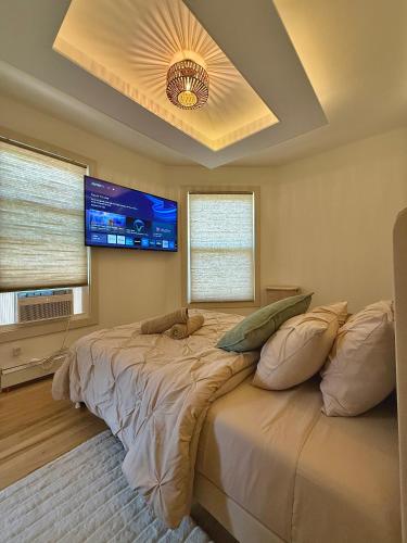 a bedroom with a large bed with a flat screen tv at Spring Rooms by Yale & Downtown in New Haven