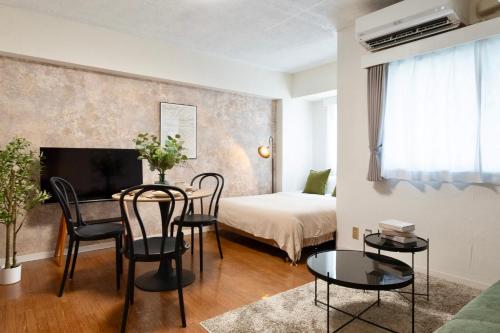 a living room with a table and chairs and a bed at Feel Stay NAGOYA in Nagoya