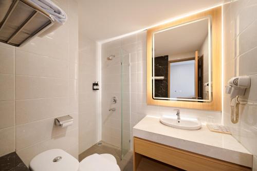 a bathroom with a sink and a toilet and a mirror at Metland Hotel Bekasi in Bekasi