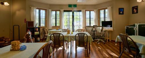 a dining room with tables and chairs and windows at カナリアンホテル in Tateshina