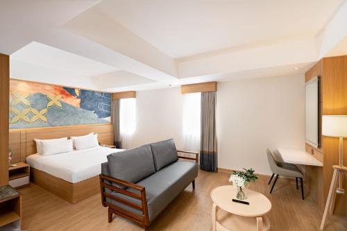 a hotel room with a bed and a couch at Metland Hotel Bekasi in Bekasi