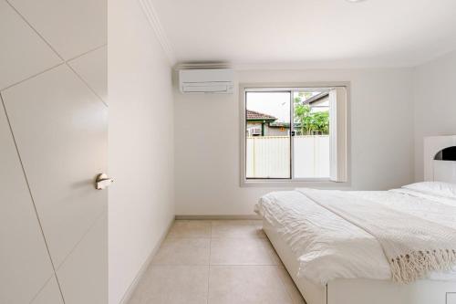 a white bedroom with a bed and a window at Brand new fully accessible 5 bedroom house in Fairfield