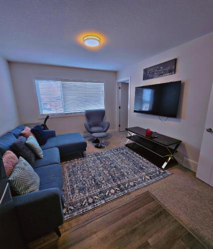 a living room with a blue couch and a flat screen tv at Atare Suite in Saskatoon