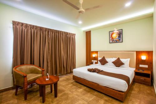 a hotel room with a bed and a chair at Hotel Maas Residency in Māvelikara