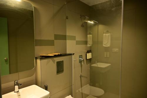 a bathroom with a shower and a toilet and a sink at Lumis Hotel Whitefield in Bangalore