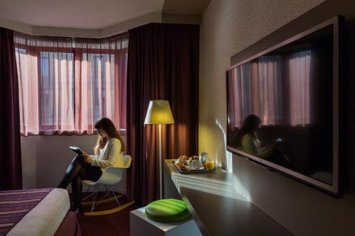 a woman sitting in a chair in a hotel room at Mercure Strasbourg Centre in Strasbourg