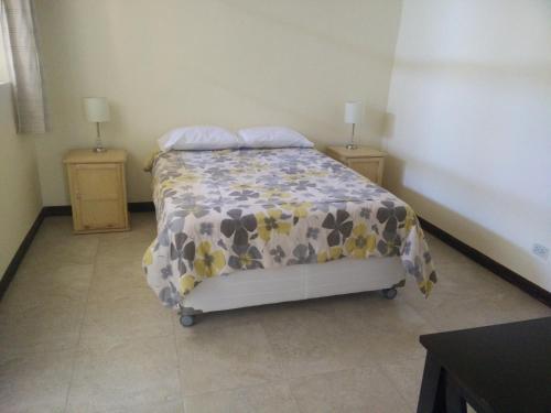 a bedroom with a bed with a flowered blanket at Wild Olive Guest House in Ica