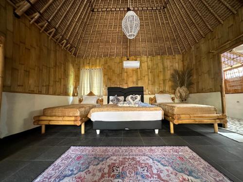 a bedroom with two beds and a rug at Bambuu in Gili Islands