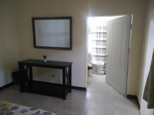 a bathroom with a toilet and a table and a mirror at Wild Olive Guest House in Ica