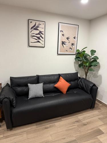 a black leather couch in a living room with three pictures at Apartment in the heart of Mexico City's historic in Mexico City