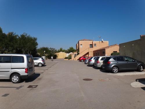 a row of parked cars in a parking lot at Résidence l'Oustal des Mers in Gruissan